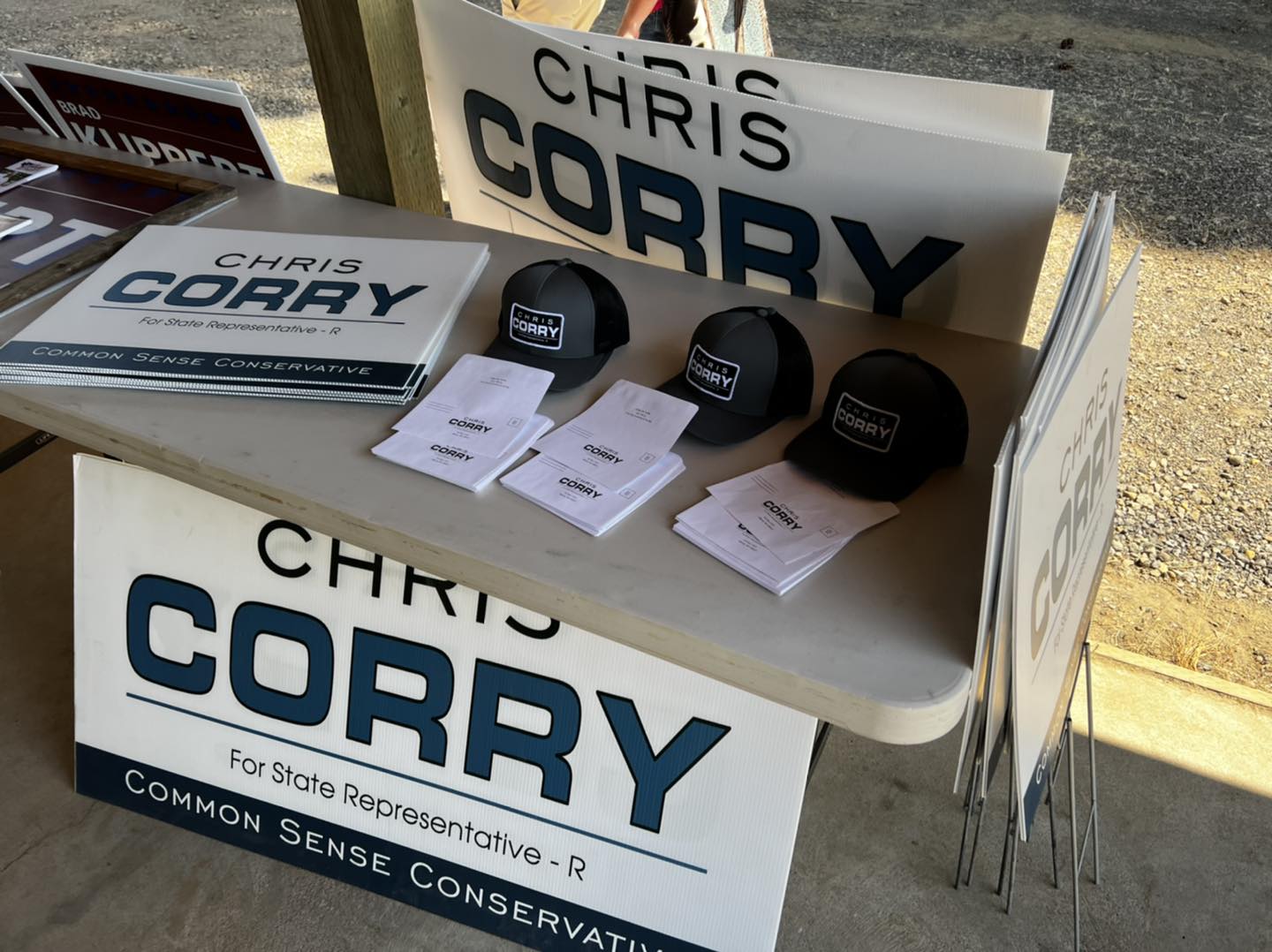 Campaign table with yard signs, hats, and literature